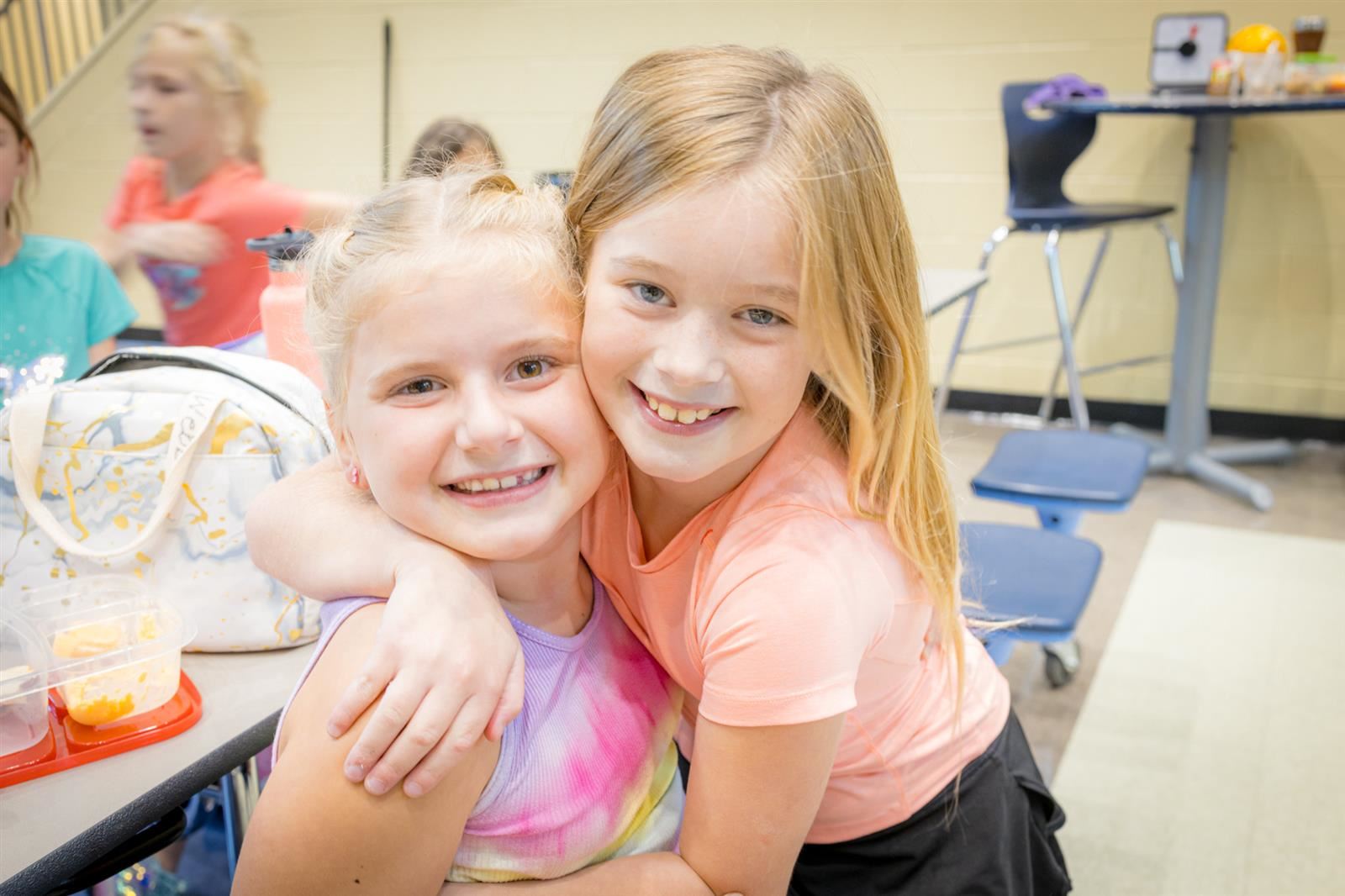 Two female friends smiling in the cafeteria